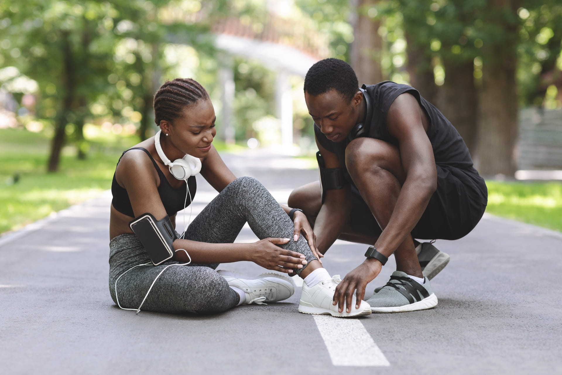 A man helping a woman with a sprain ankle in a park